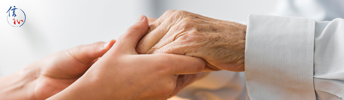 A young person holding the hand of an elderly person.
