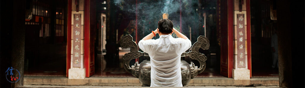 Man praying with joss sticks during Taoist funeral ritual.