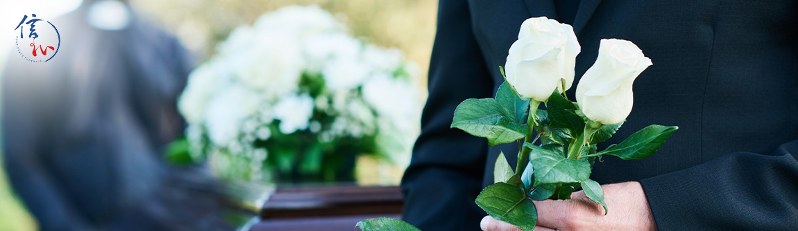 A mourner holding two white roses during a funeral service.